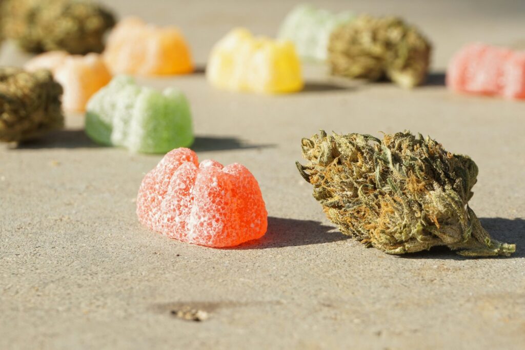 Close-up of a red cannabis gummy edible next to a cannabis flower bud